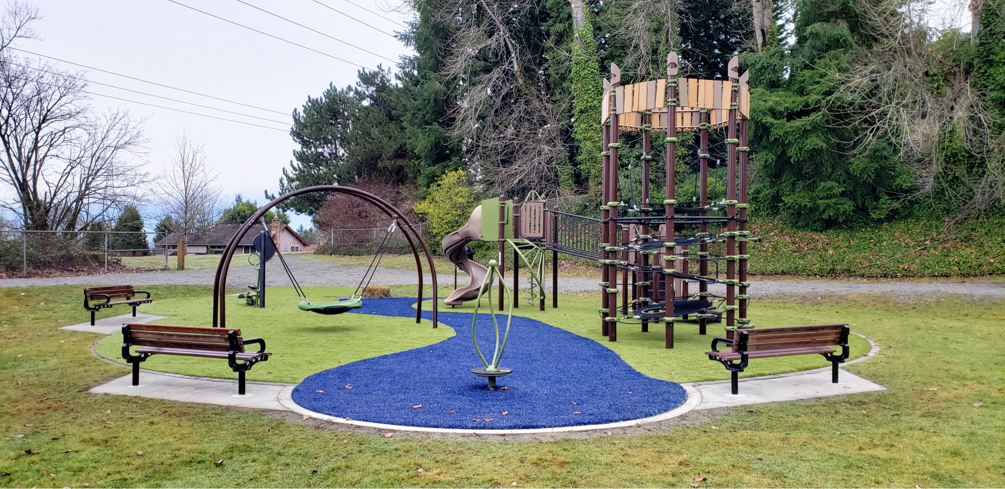 Outdoor play space with climbing structures surrounded by trees